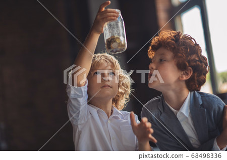 Two boys looking at the jar with coins Two boys looking at the jar with coins 68498336