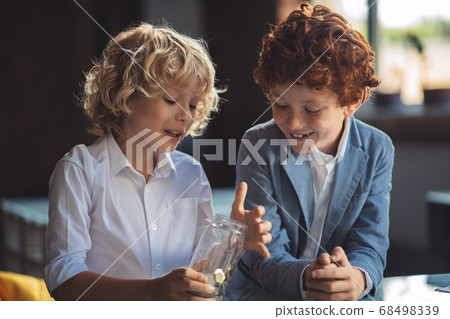 Two boys investigating the jar with coins Two boys investigating the jar with coins 68498339