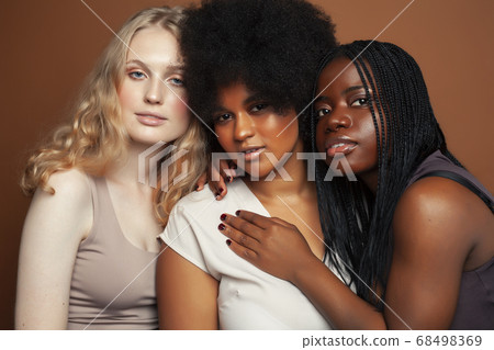 young pretty caucasian, afro, scandinavian woman posing cheerful together on brown background, lifestyle diverse nationality people concept young pretty caucasian, afro, scandinavian woman posing cheerful together on brown background, lifestyle diverse nationality people concept 68498369