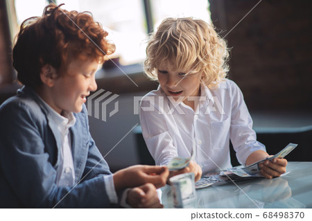 Two friends counting saved money and looking excited Two friends counting saved money and looking excited 68498370
