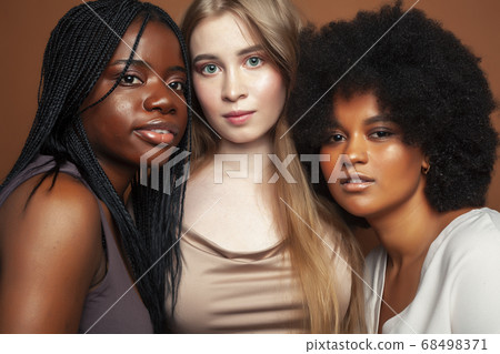 young pretty caucasian, afro, scandinavian woman posing cheerful together on brown background, lifestyle diverse nationality people concept young pretty caucasian, afro, scandinavian woman posing cheerful together on brown background, lifestyle diverse nationality people concept 68498371