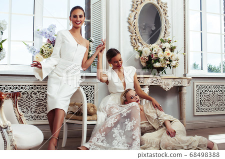 three young pretty lady in white lace fashion style dress posing in rich interior of royal hotel room, luxury lifestyle people concept, bride on wedding day 68498388