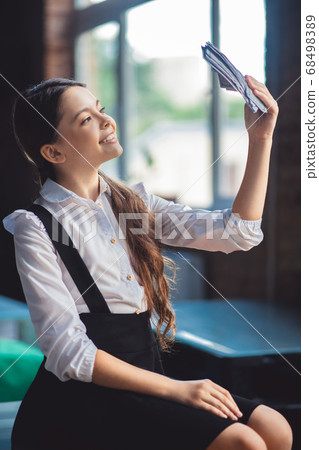 Girl in white shirt holding dollars and looking excited 68498389