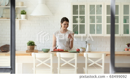 Happy young female preparing salad using recipe from internet Happy young female preparing salad using recipe from internet 68499092