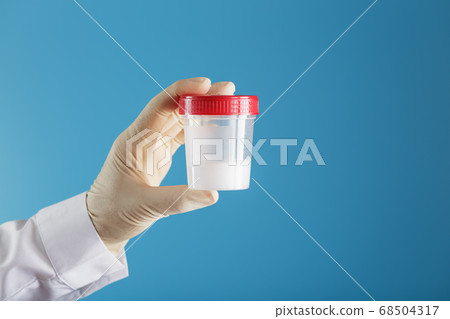 A doctor's gloved hand holding a bottle of a A doctor's gloved hand holding a bottle of a 68504317