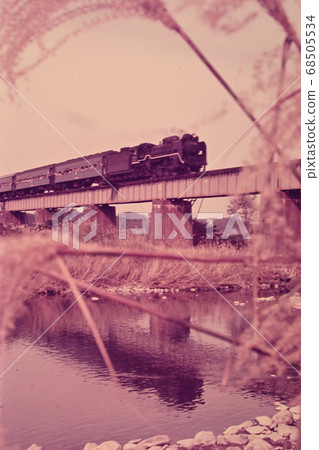 Old film photo of a steam locomotive crossing an iron bridge 68505534