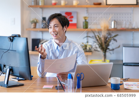Telework A young man having a web conference in his living room Telework A young man having a web conference in his living room 68505999