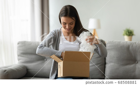 Happy young pretty woman unwrapping cardboard box. Happy young pretty woman unwrapping cardboard box. 68508881