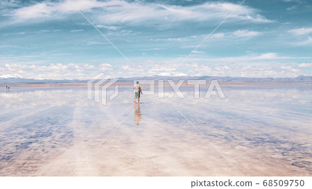 Man alone at endless salt flat Salar de Uyuni. Man silhouette and reflection in the Salar de Uyuni. Man alone at endless salt flat Salar de Uyuni. Man silhouette and reflection in the Salar de Uyuni. 68509750
