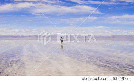 Man alone at endless salt flat Salar de Uyuni. Man silhouette and reflection in the Salar de Uyuni. 68509751