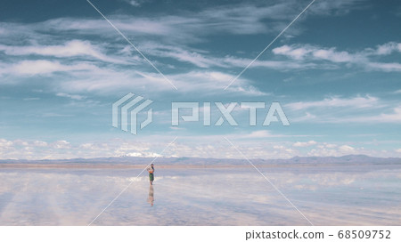 Man alone at endless salt flat Salar de Uyuni. Man silhouette and reflection in the Salar de Uyuni. Man alone at endless salt flat Salar de Uyuni. Man silhouette and reflection in the Salar de Uyuni. 68509752