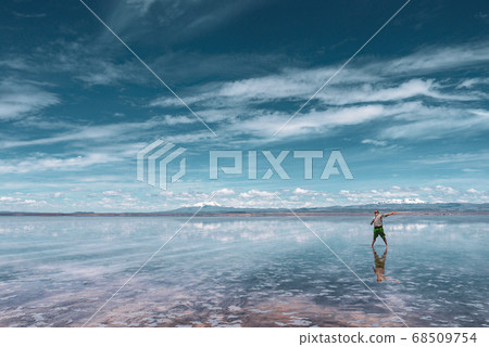 Man alone at endless salt flat Salar de Uyuni. Man silhouette and reflection in the Salar de Uyuni. 68509754