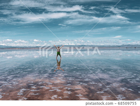 Man alone at endless salt flat Salar de Uyuni. Man silhouette and reflection in the Salar de Uyuni. 68509755