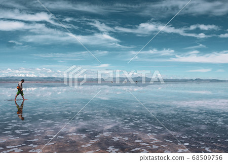 Man alone at endless salt flat Salar de Uyuni. Man silhouette and reflection in the Salar de Uyuni. Man alone at endless salt flat Salar de Uyuni. Man silhouette and reflection in the Salar de Uyuni. 68509756