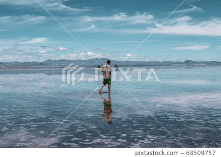 Man alone at endless salt flat Salar de Uyuni. Man silhouette and reflection in the Salar de Uyuni. Man alone at endless salt flat Salar de Uyuni. Man silhouette and reflection in the Salar de Uyuni. 68509757