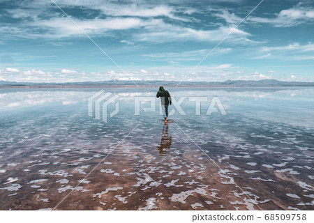 Man alone at endless salt flat Salar de Uyuni. Man silhouette and reflection in the Salar de Uyuni. Man alone at endless salt flat Salar de Uyuni. Man silhouette and reflection in the Salar de Uyuni. 68509758