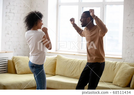 Active young african couple dancing in living room at home 68511434