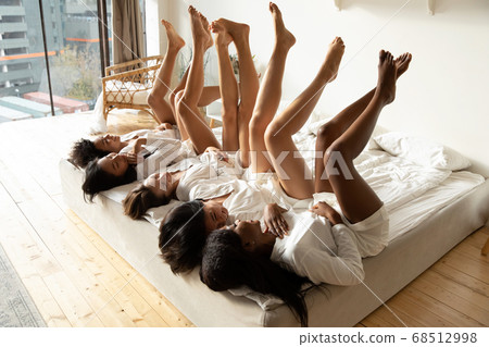 Women wearing bathrobes lying in bed raised slim legs up 68512998