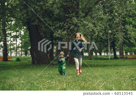 Funny kid in rain boots playing in a rain park Funny kid in rain boots playing in a rain park 68513545