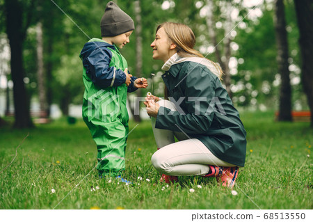 Funny kid in rain boots playing in a rain park 68513550