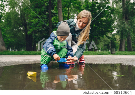 Funny kid in rain boots playing in a rain park Funny kid in rain boots playing in a rain park 68513664