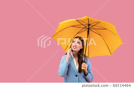 Portrait of angry young girl holding yellow umbrella Portrait of angry young girl holding yellow umbrella 68514464