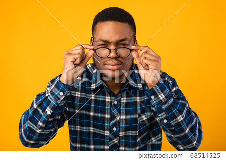 Man In Eyeglasses Looking At Camera Squinting Eyes, Yellow Background Man In Eyeglasses Looking At Camera Squinting Eyes, Yellow Background 68514525