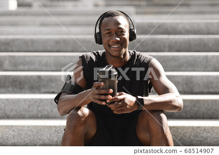 Black Guy Resting After Jogging Outdoors, Listening Music And Having Protein Drink Black Guy Resting After Jogging Outdoors, Listening Music And Having Protein Drink 68514907