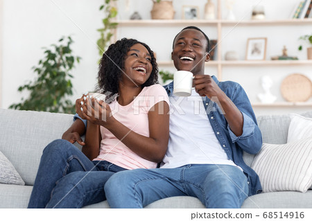 Black couple enjoying weekend together, drinking coffee on couch Black couple enjoying weekend together, drinking coffee on couch 68514916