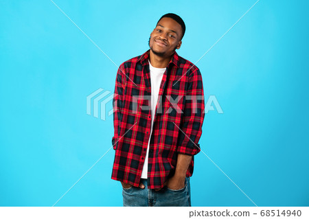 African Guy Holding Hands In Pockets On Blue Studio Background 68514940