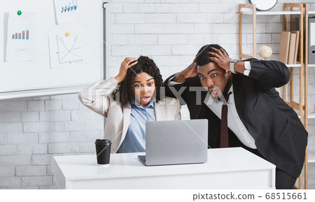 Black colleagues looking at laptop screen in terror, finding mistake in business project at modern office Black colleagues looking at laptop screen in terror, finding mistake in business project at modern office 68515661