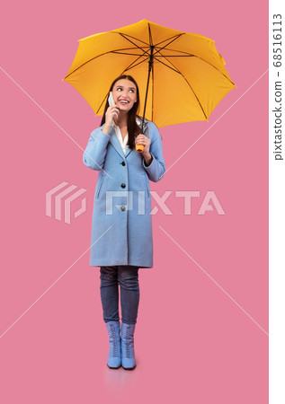 Portrait of smiling young girl holding yellow umbrella Portrait of smiling young girl holding yellow umbrella 68516113