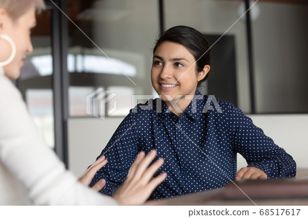 Smiling young indian businesswoman holding pleasant conversation with european colleague. 68517617