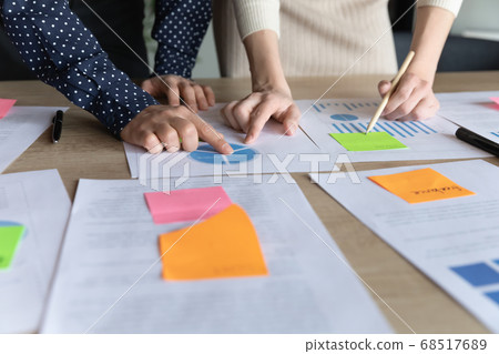 Close up two multiracial business women analyzing marketing research charts. Close up two multiracial business women analyzing marketing research charts. 68517689