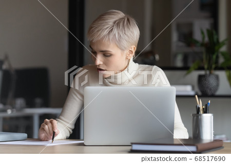 Focused young businesswoman reading contract terms of conditions. Focused young businesswoman reading contract terms of conditions. 68517690