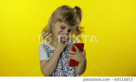 Child girl scrolling social network posts on smartphone. Remote online shopping, browsing on phone. 68518853