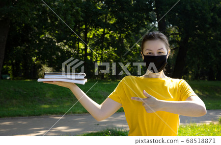 Beautiful female college student in black protective mask in a park outdoors  68518871