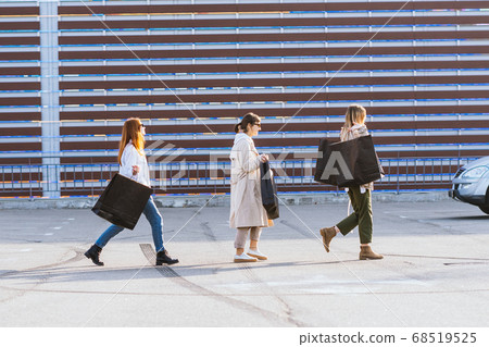 Young women with shopping bags walking on street. 68519525