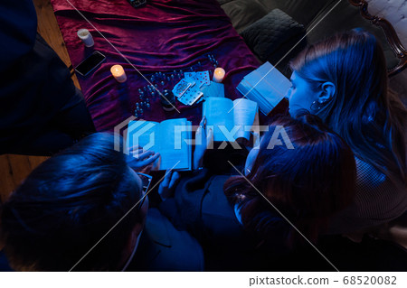 Two women and a guy are reading a mysterious books, close view Two women and a guy are reading a mysterious books, close view 68520082