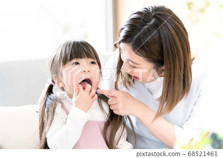 Mother checking daughter's teeth 68521461