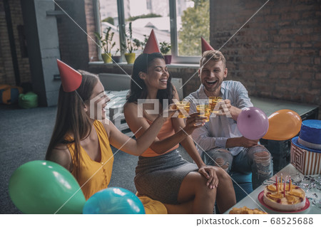 Joyful young friends drinking alcohol during the birthday party Joyful young friends drinking alcohol during the birthday party 68525688