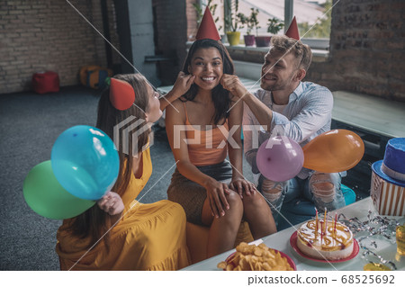 Friends touching womens cheeks during the birthday party 68525692