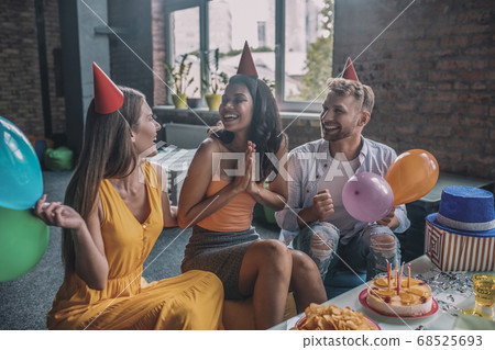 Two women and a man celebrating a birthday together Two women and a man celebrating a birthday together 68525693