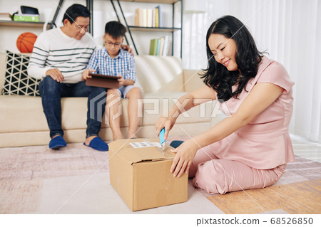 Smiling woman opening cardboard box 68526850