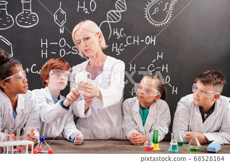 Teacher of chemistry in whitecoat showing mixture of two chemical substances Teacher of chemistry in whitecoat showing mixture of two chemical substances 68528164