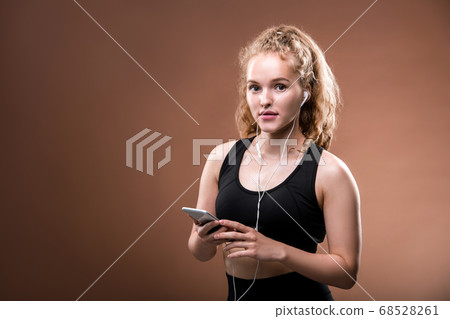 Young cheerful sportswoman in activewear and earphones scrolling in smartphone Young cheerful sportswoman in activewear and earphones scrolling in smartphone 68528261