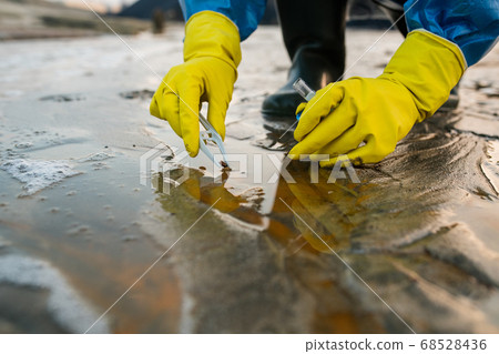 Hands of contemporary ecologist sitting on squats while taking sample of soil 68528436