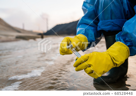 Contemporary ecologist in rubber gloves and boots and protective blue coveralls 68528448