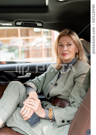 Businesswoman sitting on backseat of taxi cab on her way to appointment 68528490