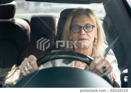 Successful blond elegant businesswoman in eyeglasses driving to work Successful blond elegant businesswoman in eyeglasses driving to work 68528520